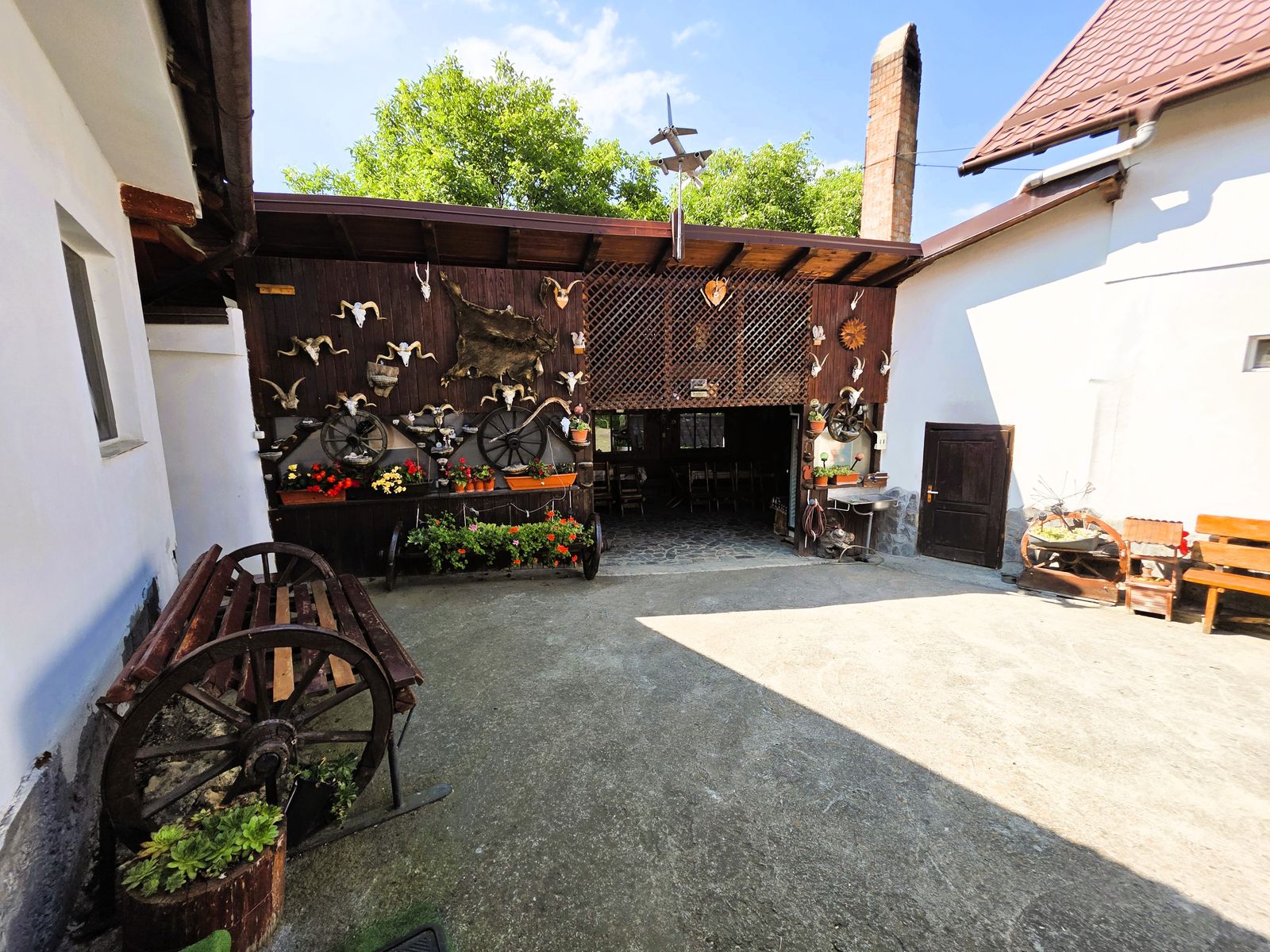 Foișor rustic acoperit la intrarea din curte, decorat cu unelte tradiționale